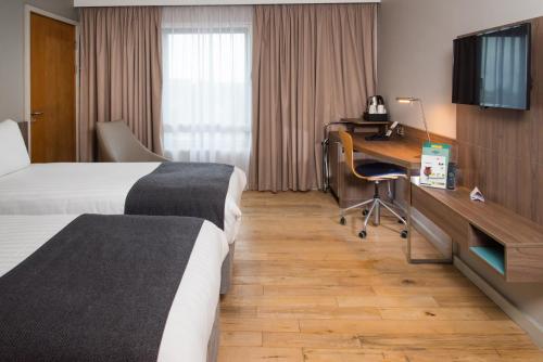 a hotel room with two beds and a desk at Holiday Inn London West by IHG in London