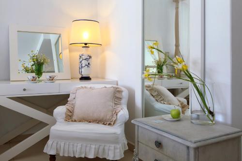 a white room with a chair and a table with a lamp at Mare Monte Small Boutique Hotel in Chrysi Ammoudia