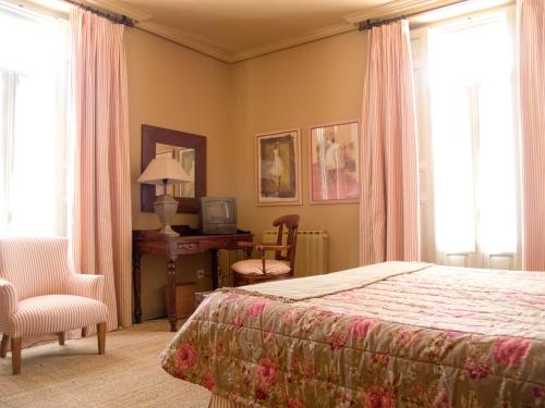 a bedroom with a bed and a desk and a chair at Hotel Roma in La Granja de San Ildefonso