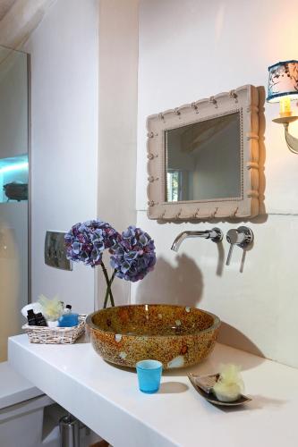 a bathroom with a bowl sink and flowers on a counter at Mare Monte Small Boutique Hotel in Chrysi Ammoudia