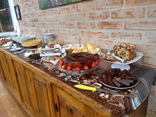 a buffet filled with different types of cakes and desserts at Pousada Casa Pinha em Campos do Jordão in Campos do Jordão