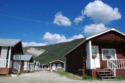 a row of wooden buildings with a mountain in the background at Triple J Hotel in Dawson City