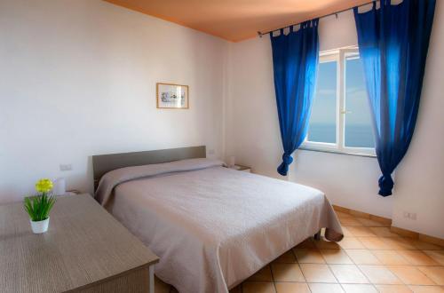 フローレにあるFurore Coast Roomsのベッドルーム1室(ベッド1台、青いカーテン付きの窓付)