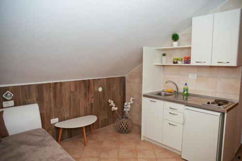 a small kitchen with white cabinets and a table at Guesthouse Anita in Kotor