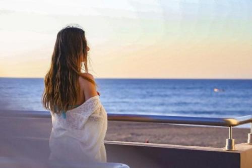 a woman in a white dress looking out at the ocean at Casa Margarita Hotel And Paradise in Las Lisas
