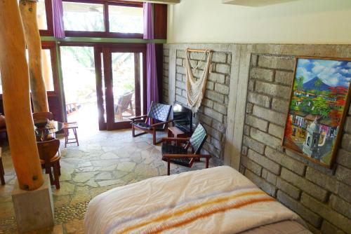 a bedroom with a bed and chairs and a brick wall at Luxury Studio Suite in San Juan del Sur