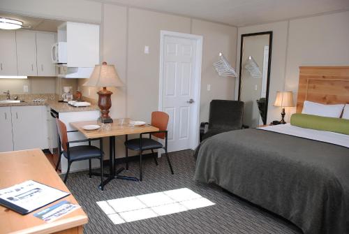 ドーソン・シティにあるTriple J Hotelのベッド、テーブル、キッチンが備わるホテルルームです。