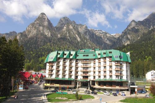 a large hotel with mountains in the background at Hotel Silva Busteni in Buşteni