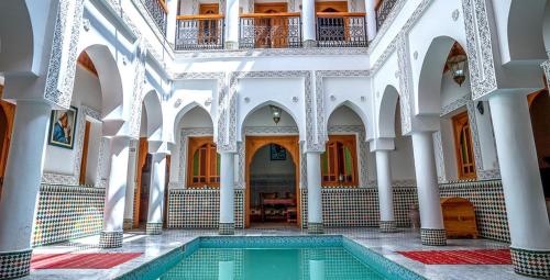 einen Innenpool in einem Gebäude mit Säulen und Decken in der Unterkunft Riad Moulay Spa in Marrakesch