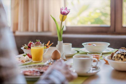 a table with breakfast foods and a flower in a vase at Pension Christl in Caldaro