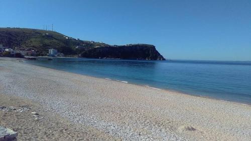 a beach with blue water and a hill at Guest House Solive in Himare