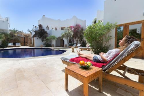 a woman laying in a chair on a patio next to a pool at Red C Villas in Dahab
