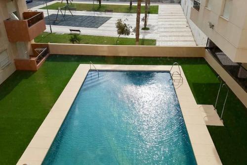widok na basen z zieloną trawą w obiekcie Apartamento Roquetas playa con WIFI w mieście Roquetas de Mar