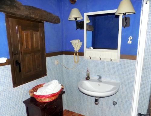 Un baño azul con lavabo y espejo. en Casas Rurales Lagunas de Ruidera - Piscina, en Ossa de Montiel