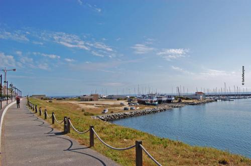 a person walking down a sidewalk next to a river at Vasco da Gama in Póvoa de Varzim