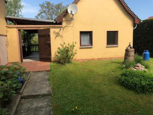 a yellow house with a door and a yard at Peeneurlaub in Lassan