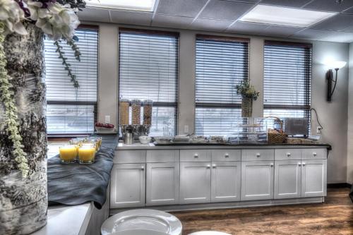 a kitchen with a counter with two sinks and windows at Podollan Inn & Spa - Grande Prairie in Grande Prairie