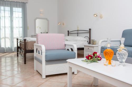 a living room with two beds and a table with flowers at Golden Bay in Agios Prokopios