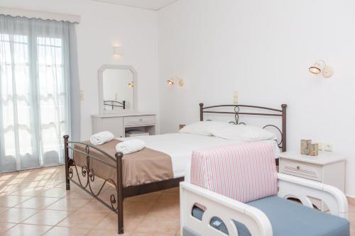 a bedroom with a bed and a mirror and a chair at Golden Bay in Agios Prokopios