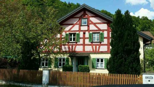 a red and white house with a wooden fence at Ferienhaus am Mühlbach in Kinding