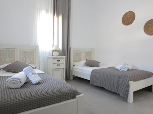 a white bedroom with two beds with towels on them at Bonatsa House in Agios Georgios