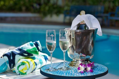 two glasses of wine on a table next to a pool at The Gardens Hotel in Key West