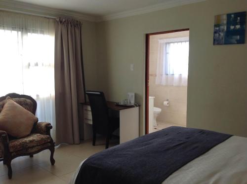 a bedroom with a bed and a chair and a desk at Vinolux Guest House in Mthatha