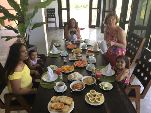 a group of people sitting around a table with food at Sath Villa Naadi Ayurveda Resort in Moragalla