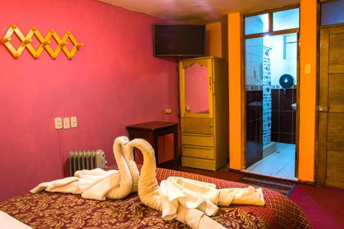 Una habitación con una cama con dos cisnes. en Hostal Virgen de Las Nieves II, en Puno