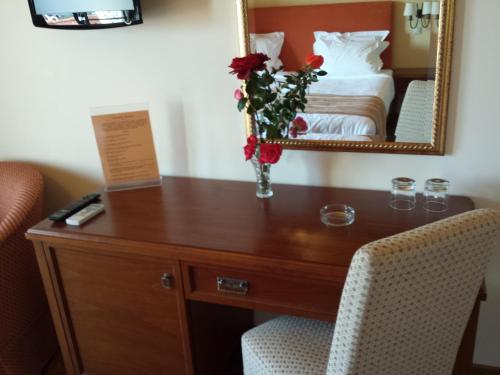 a desk with a vase of flowers on it in a hotel room at Hotel Pelasgos in Karítaina