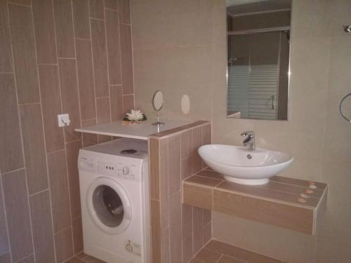 a bathroom with a washing machine and a sink at Maria's Garden in Galatás