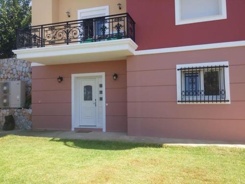 a pink house with a white door and a balcony at Maria's Garden in Galatás