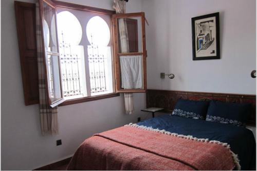 a bedroom with a bed and two windows at Hôtel Ras El Maa in Chefchaouene