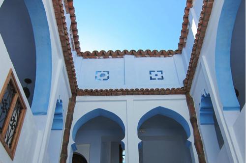 a blue and white building with arches and a roof at Hôtel Ras El Maa in Chefchaouene