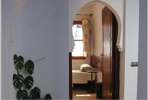 a room with a bedroom with a bed and an open door at Hôtel Ras El Maa in Chefchaouene