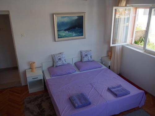 a bedroom with a purple bed and two windows at Beachfront Apartment Jelsa in Jelsa