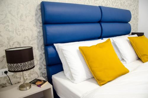 a bed with a blue headboard and yellow pillows at San Martino Rooms in Pula