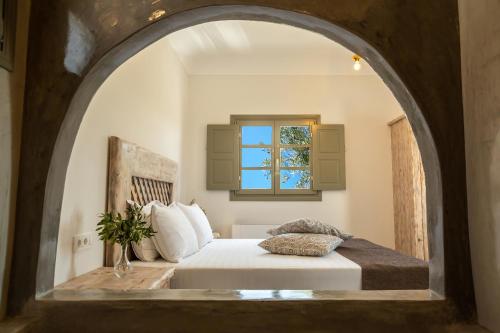 Elixirium villa في بيريسا: غرفة نوم مع سرير مع نافذة مقوسة
