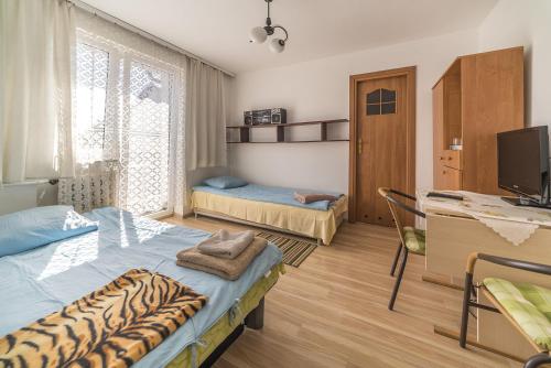 ヤスタルニャにあるpokoje gościnne u Ewyのベッド2台、デスク、テレビが備わる客室です。