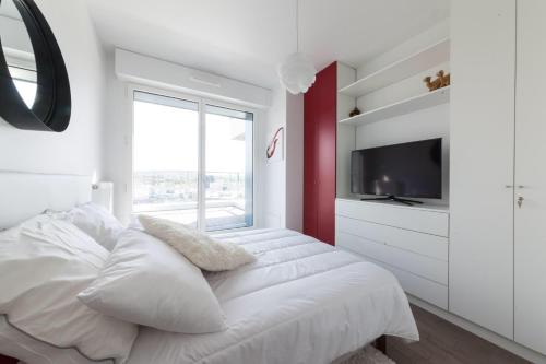 - une chambre blanche avec un grand lit et une télévision dans l'établissement Porte de Versailles et Parc des Princes, à Issy-les-Moulineaux