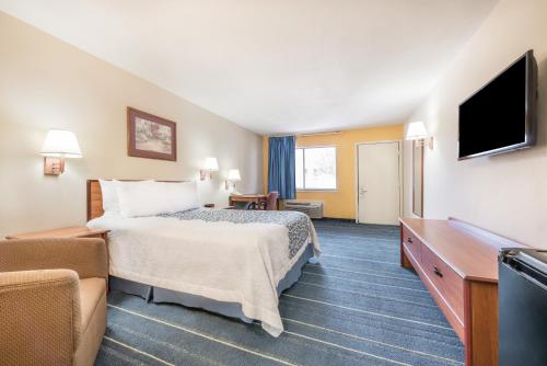 a hotel room with a bed and a flat screen tv at Days Inn by Wyndham Bryan College Station in College Station