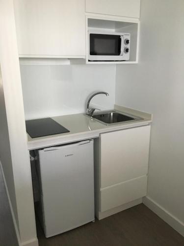 a small kitchen with a sink and a microwave at Micasa Inn Fátima in Fátima