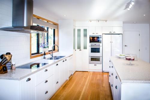 a kitchen with white cabinets and a wooden floor at Wanaka Tree & Lake House in Wanaka