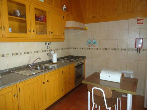 uma cozinha com armários de madeira, um lavatório e um balcão em Casa Campo e Praia em Rogil