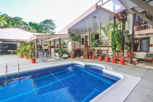 a house with a swimming pool in front of a house at Hotel Flor Blanca in Manuel Antonio