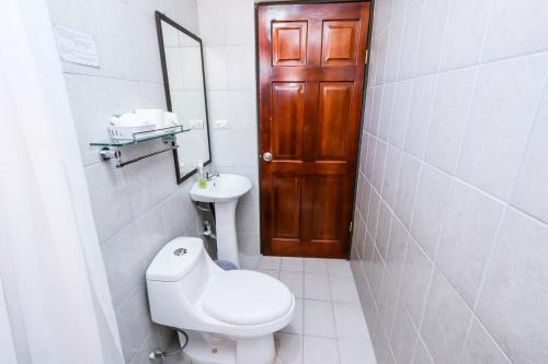 a bathroom with a toilet and a sink and a mirror at Hotel Flor Blanca in Manuel Antonio
