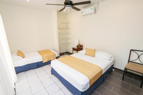 a room with two beds and a chair at Hotel Flor Blanca in Manuel Antonio