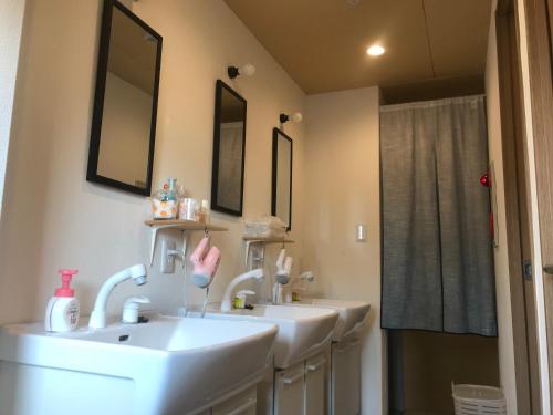 a bathroom with three sinks and two mirrors at Guesthouse Sensu in Tokyo