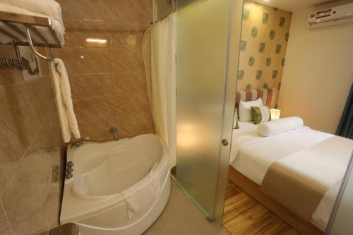 Thuy Sakura Hotel & Serviced Apartment في مدينة هوشي منه: حمام مع دش زجاجي مع سرير
