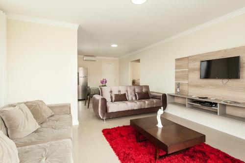 - un salon avec un canapé et une télévision dans l'établissement Jurerê Sol & Mar Temporada, à Florianópolis